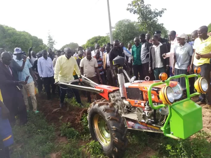 Hon. Denis Hamson Obua while manning the hand-held tractor during the handover